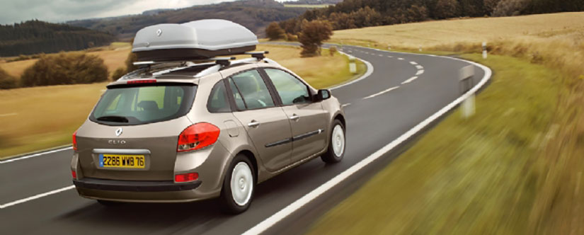 Renault Clio with roof box on winding country road