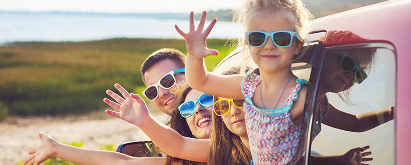 Kids waving outside car window in summer