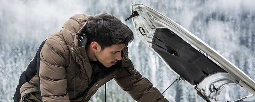 Man inspecting his car engine in winter
