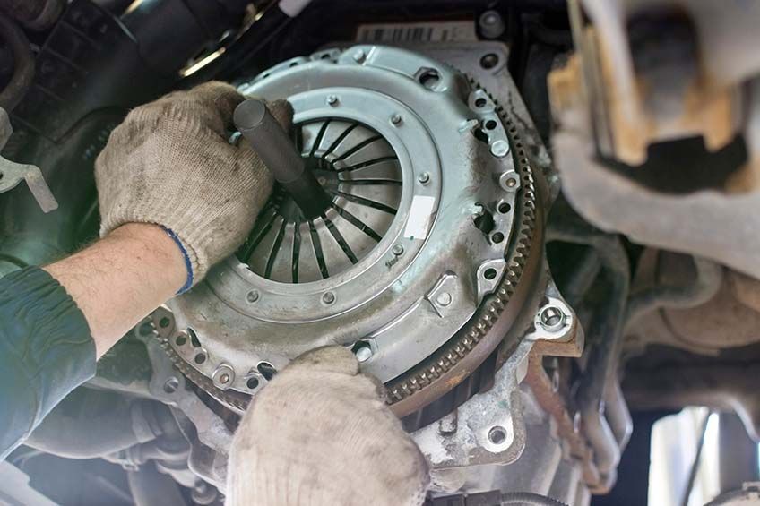 a mechanic removes an old, worn car clutch that needs replacing.