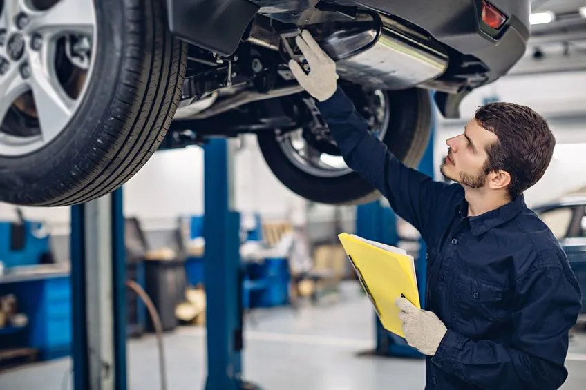 a mechanic inspects the underside of a car during a regular vehicle service.